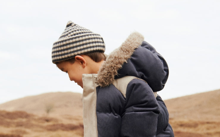 Child in winter clothing standing in a desert-like landscape