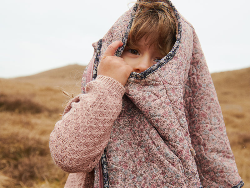 Child wrapped in a pink floral vest in a field